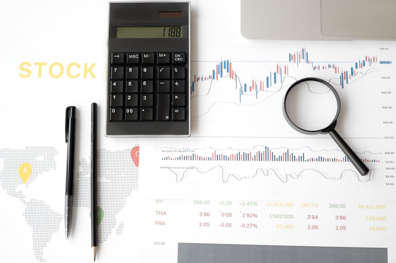 home-services-02 Flat lay of stock market analysis tools including calculator, graphs, and magnifying glass.